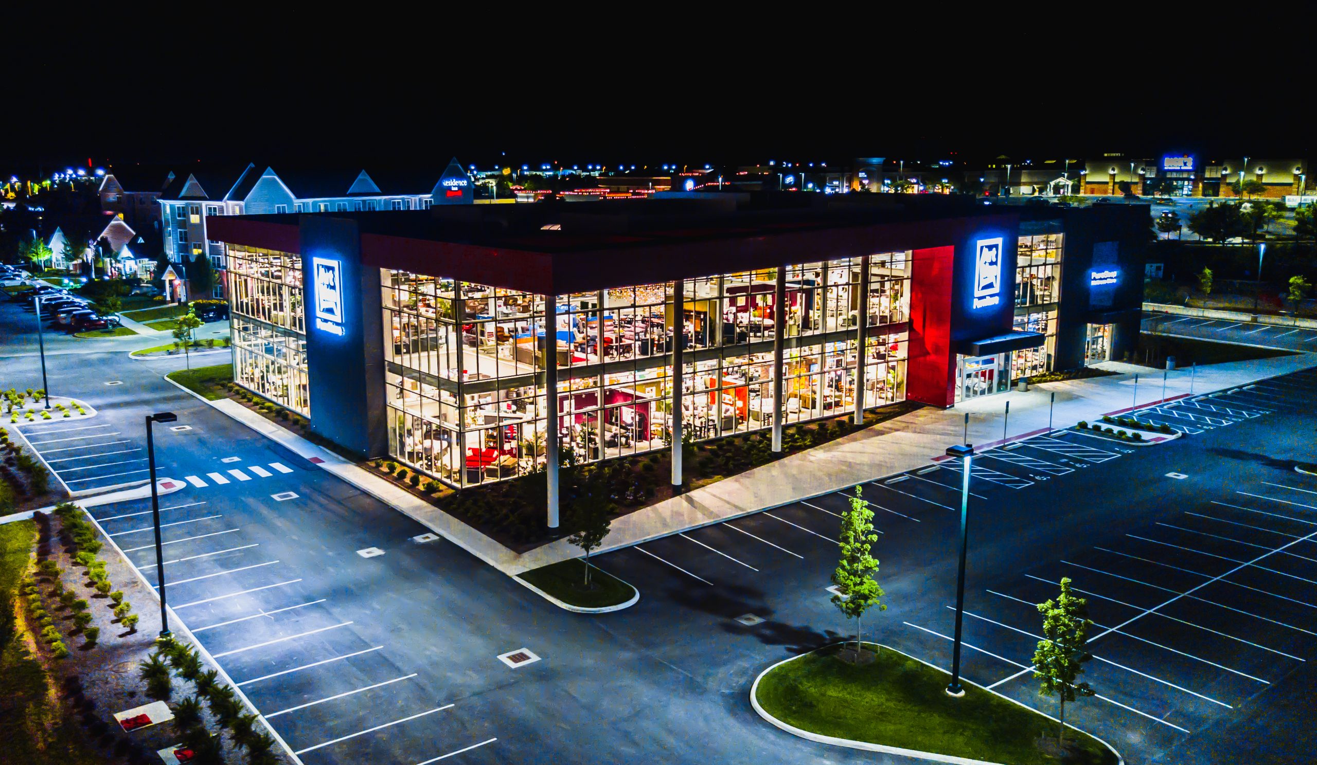 Modern glass-walled furniture showroom photographed at night in a commercial real estate development
