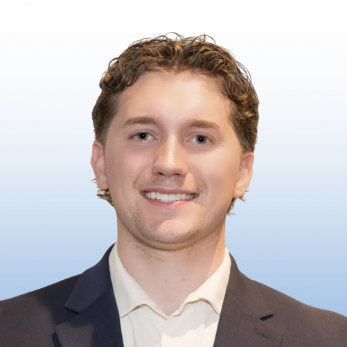 Professional headshot of a smiling Equity team member with curly brown hair wearing a dark blazer and white shirt.