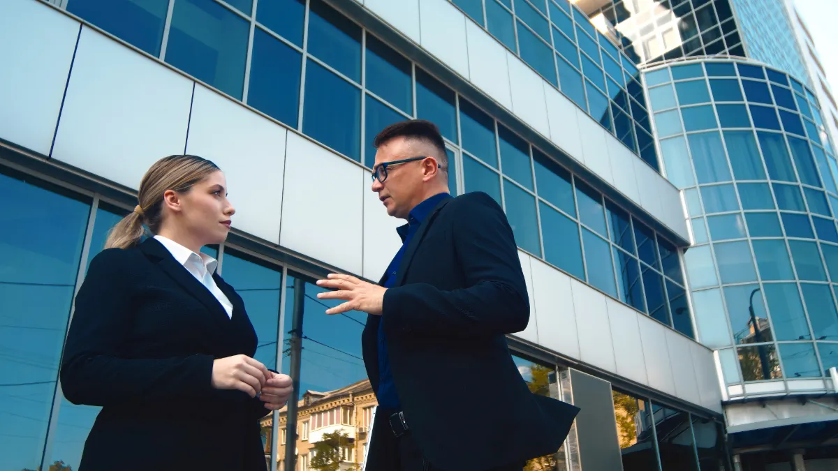 Commercial real estate advisors meeting outside a modern glass office building